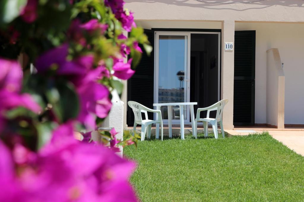 dos sillas y una mesa en un césped con flores púrpuras en Apartamento Saura, en Cala en Blanes