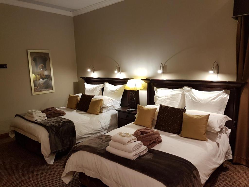 Cornerstone Guest Lodge في بريتوريا: غرفه فندقيه سريرين عليها مناشف