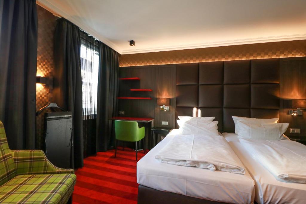 a hotel room with a large bed and a chair at Hotel Haverkamp in Bremerhaven