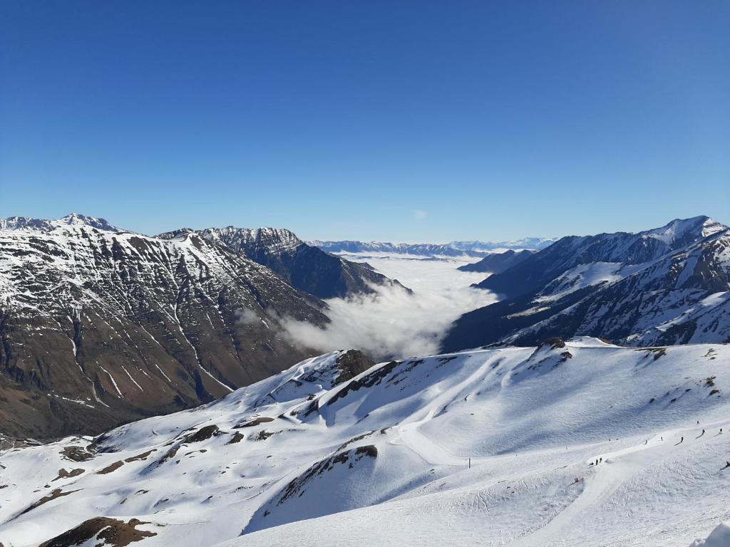 eine schneebedeckte Bergkette mit Wolken in der Ferne in der Unterkunft Les Pioupious de Club Engaly 2 pour 4 personnes in Aragnouet