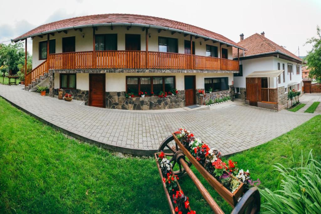 a large house with a porch and flowers in the yard at Gyöngyvirág Panzió in Lupeni