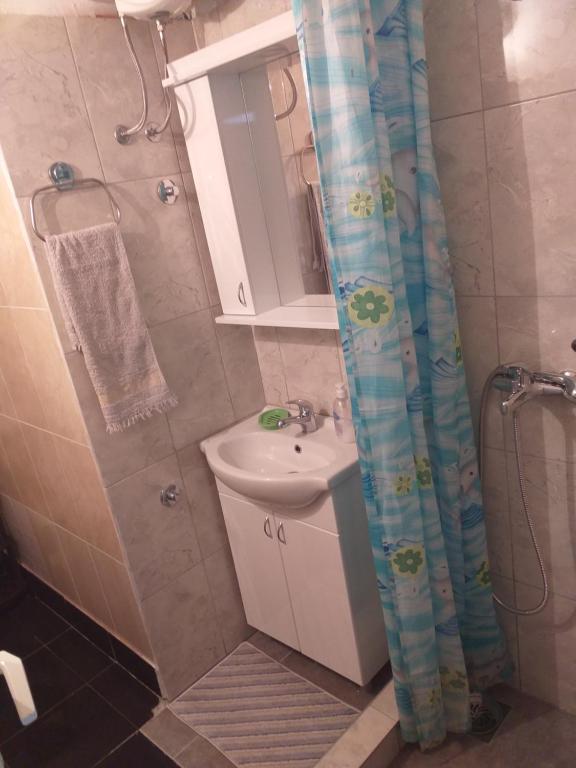 a bathroom with a sink and a shower curtain at Vikendica Iva in Perućac