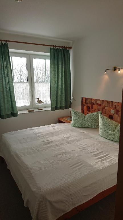 a bedroom with a large white bed with green curtains at Herzmuschel Gollwitz in Insel Poel