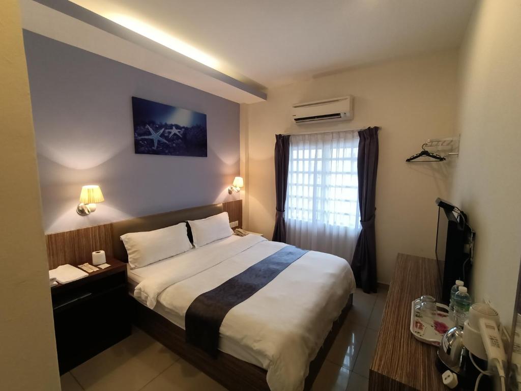 um quarto de hotel com uma cama e uma janela em Oscar Suites Hotel em Sitiawan