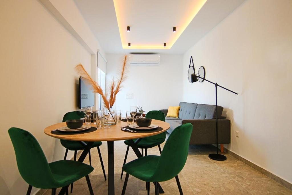 een eetkamer met een tafel en groene stoelen bij Phaedrus Living: Seaside Luxury Flat Lighthouse 69 in Paphos City