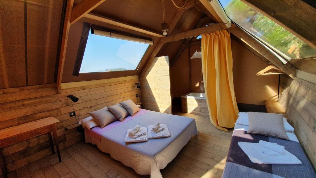 sypialnia z łóżkiem i oknem w pokoju w obiekcie Agricamping La Gallinella w mieście Castagneto Carducci