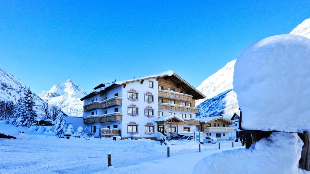 a building in the snow with mountains in the background at Hotel Galtürerhof in Galtür