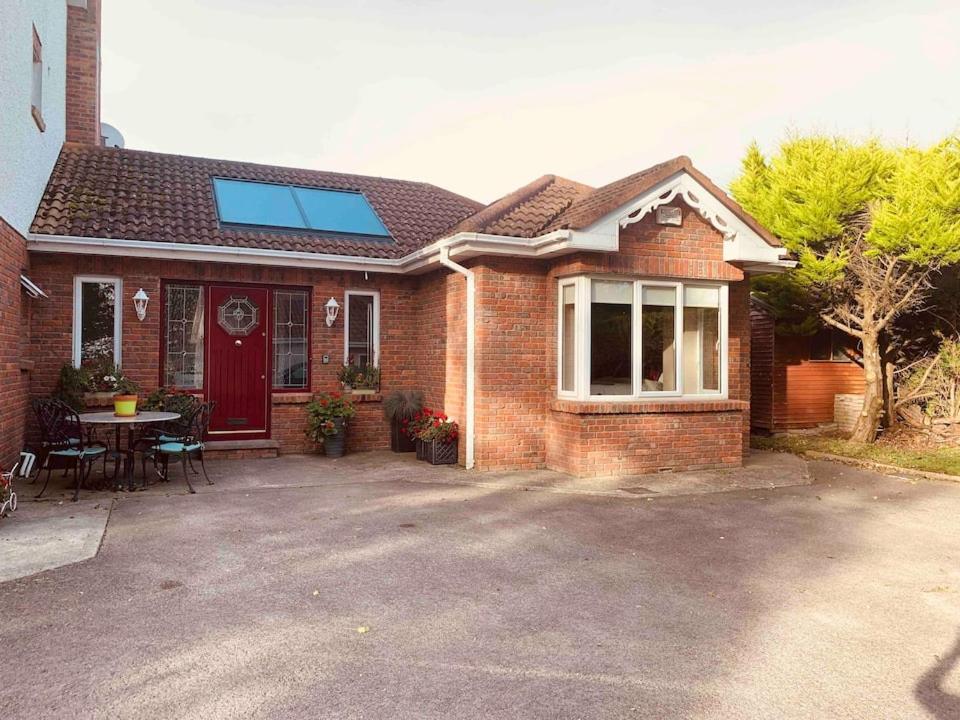 a brick house with a red door and a table at Arden Bungalow in Baltray