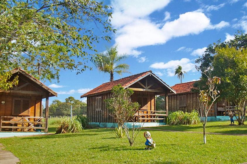 a child sitting in the grass in front of a house at Pousada Sabiá in Brotas
