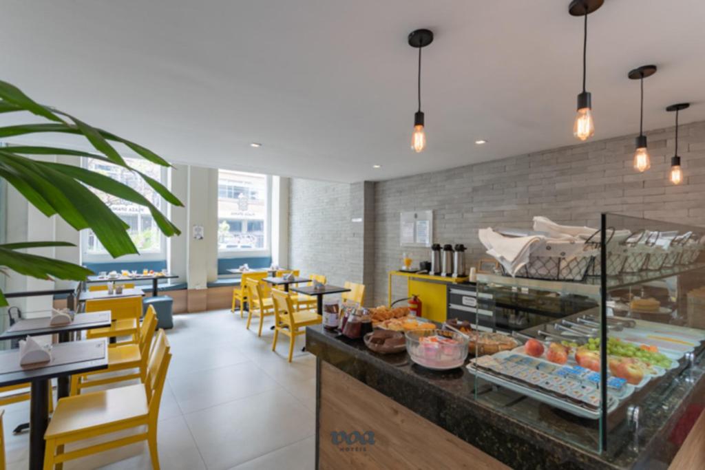 a restaurant with yellow chairs and a counter with food at Plaza Spania Boutique Hotel in Rio de Janeiro