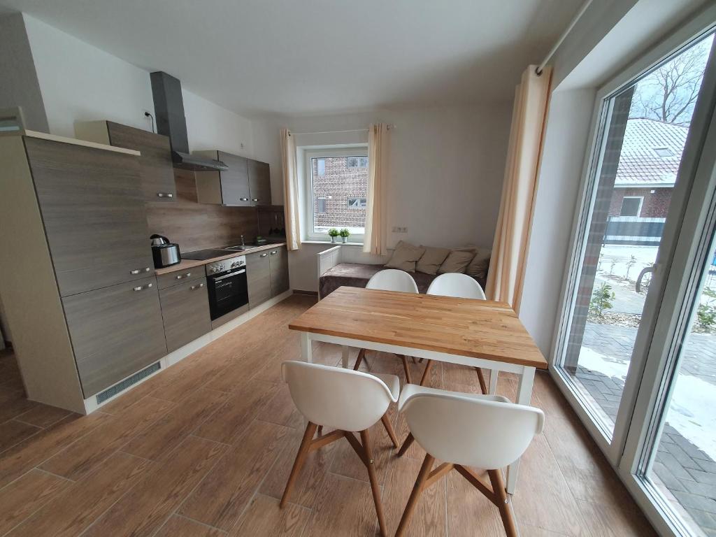 a kitchen and dining room with a wooden table and chairs at Haus Taybeerweg in Aurich