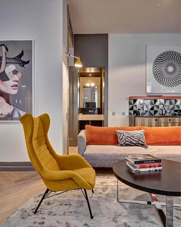 a living room with a yellow chair and a couch at H15 Boutique Hotel, Warsaw, a Member of Design Hotels in Warsaw