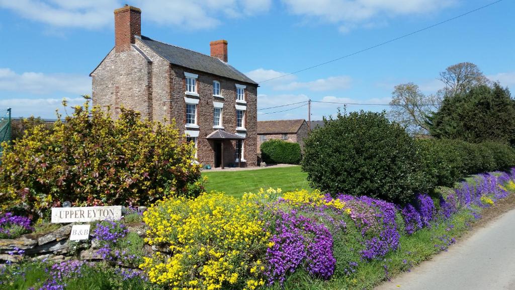 a house with a garden of flowers in front of it at Upper Eyton Farmhouse B&B in Shrewsbury