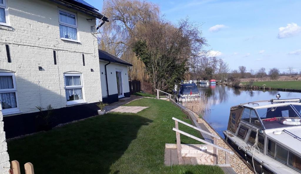 a house with a boat parked next to a canal at Riverside Cottage in Hilgay