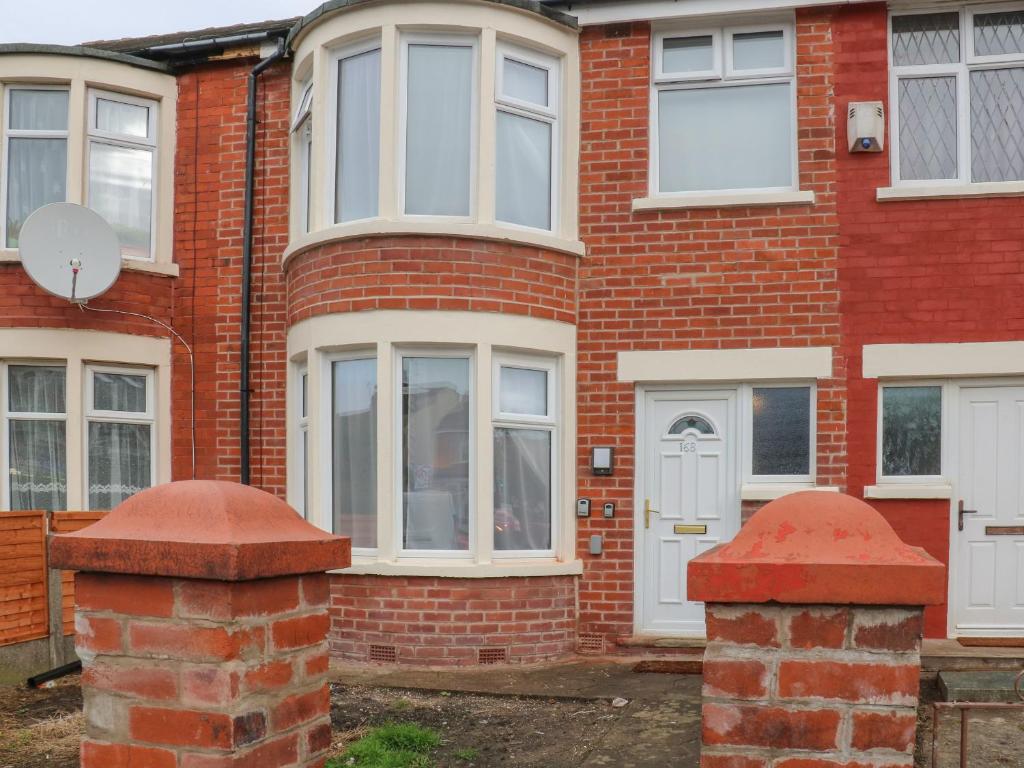 a red brick house with a white door and windows at Park Road in Blackpool