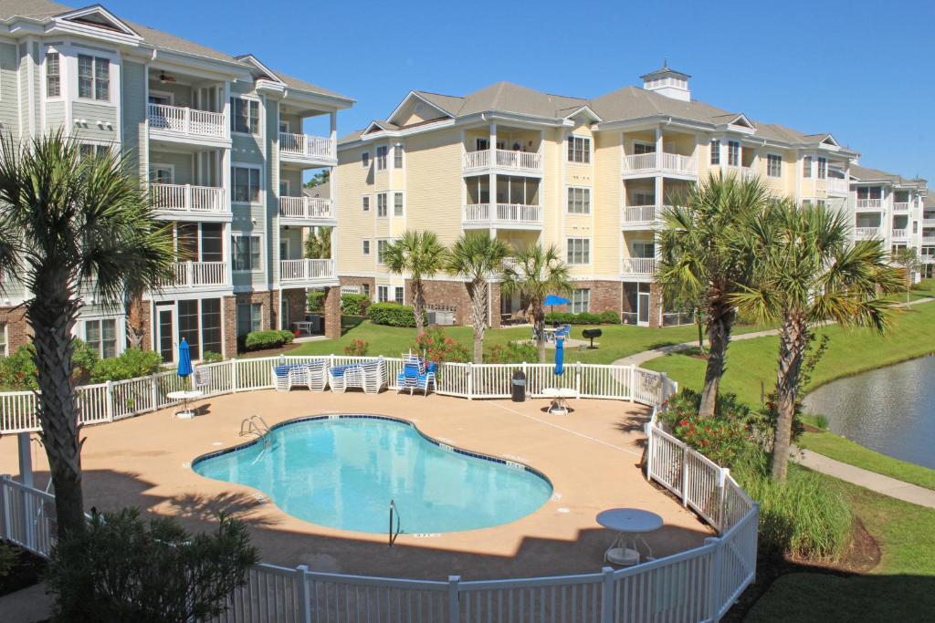 an image of a swimming pool in front of apartment complexes at Magnolia Pointe by Palmetto Vacations in Myrtle Beach