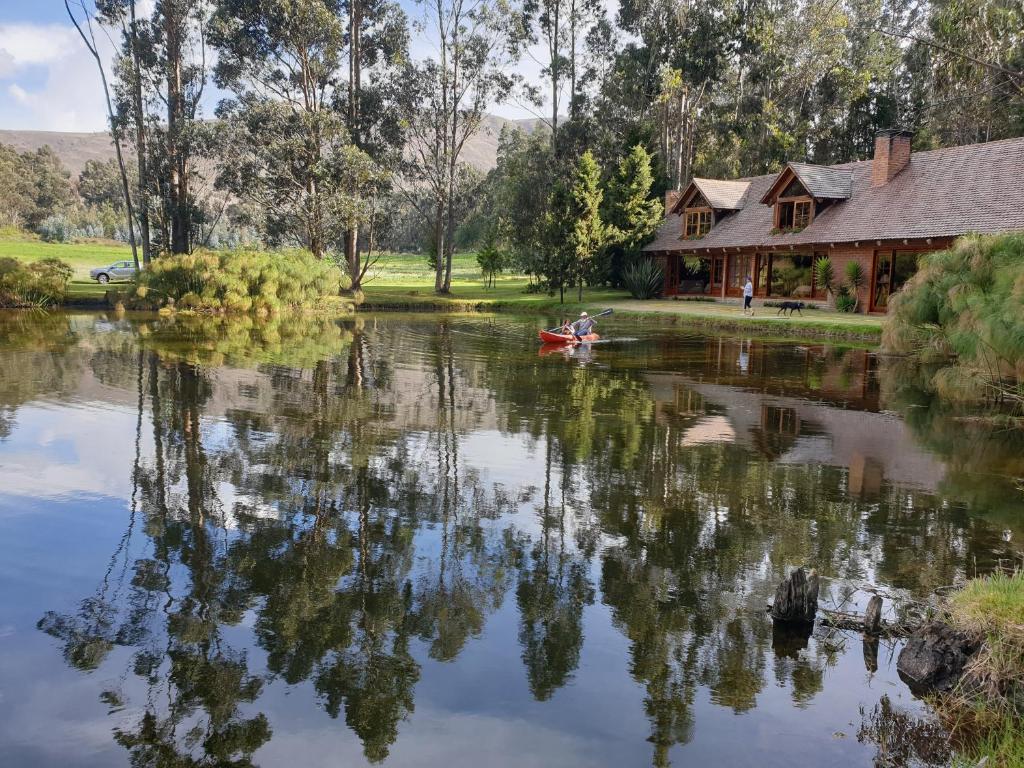 eine Person in einem Boot auf einem Fluss neben einem Haus in der Unterkunft Palumbo Glamping & Villas in Cayambe