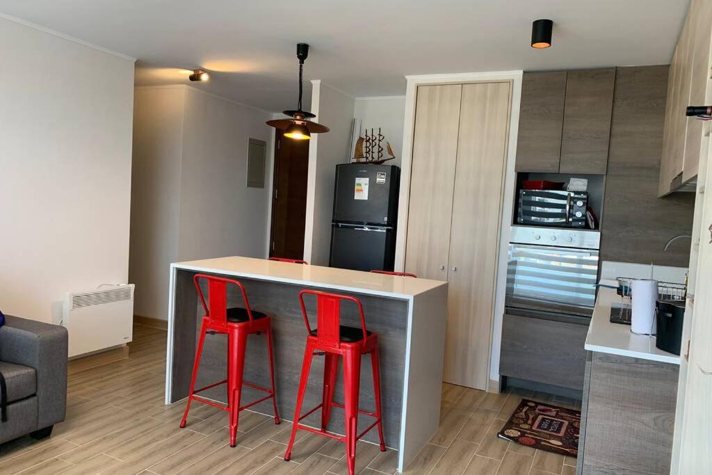 a kitchen with two red stools at a kitchen counter at Arriendo departamento excelente ubicación por día in Viña del Mar
