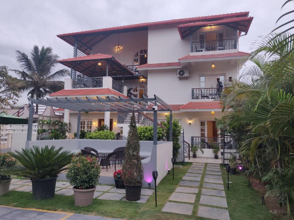 ein großes weißes Haus mit einem Tisch und Stühlen in der Unterkunft Elegant holiday homes Coorg in Madikeri