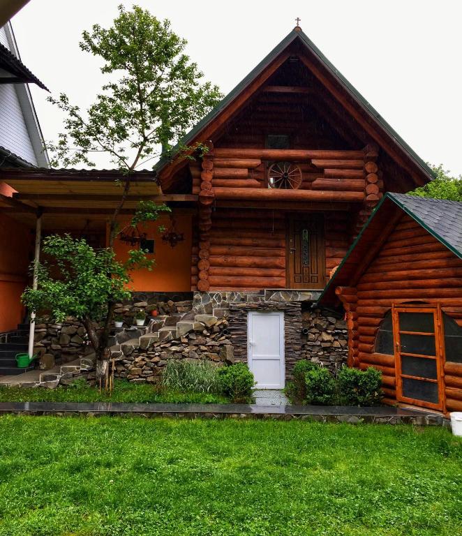 a log cabin with a white door and a window at Садиба BETWEEN MOUNTAINS in Mizhhirya