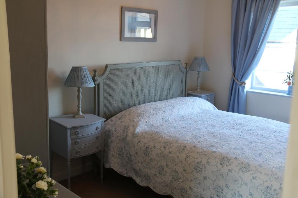 um quarto com uma cama, 2 candeeiros e uma janela em The Boathouse for two, St Davids, Garage Parking em St. Davids