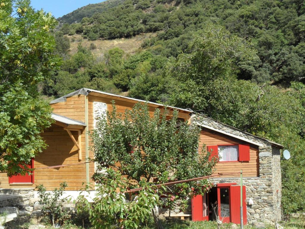 Casa de madera con puertas rojas y montaña en Le Fenil d'Evol, en Olette