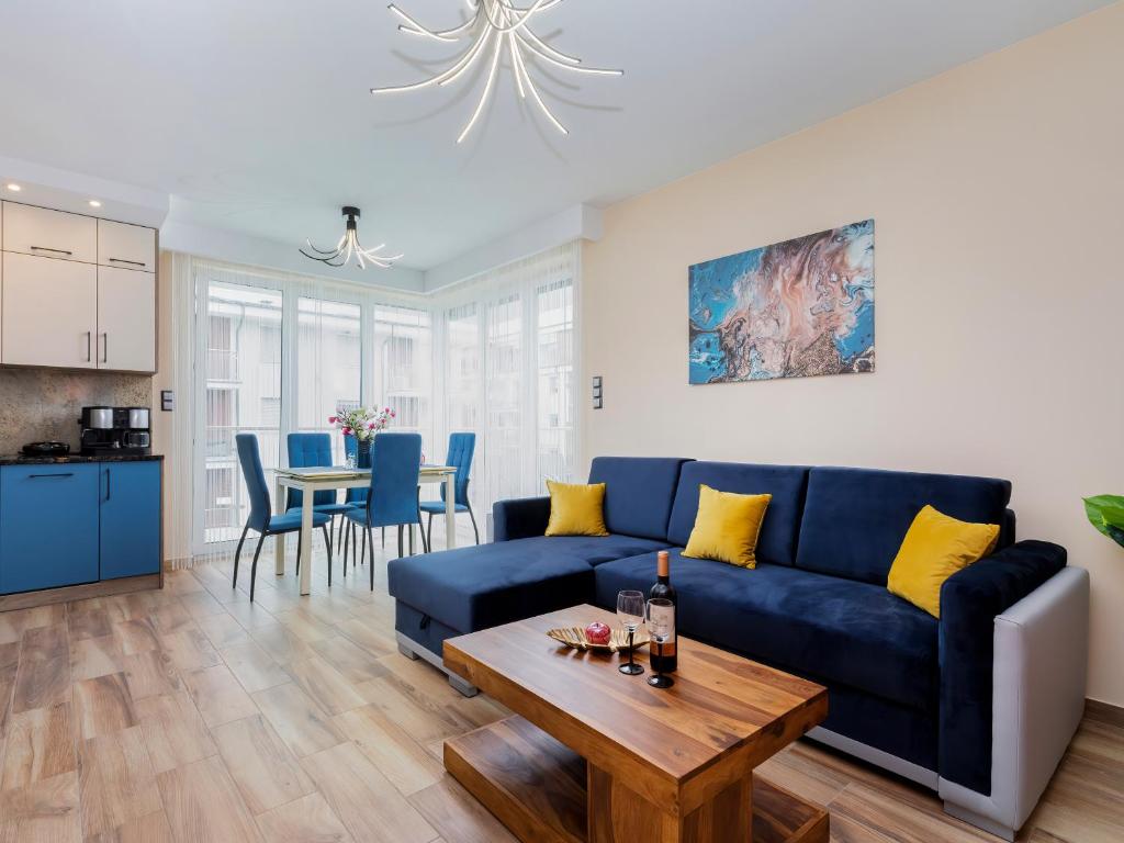 a living room with a blue couch and a table at Apartament Porto Santa Rewales in Rewal