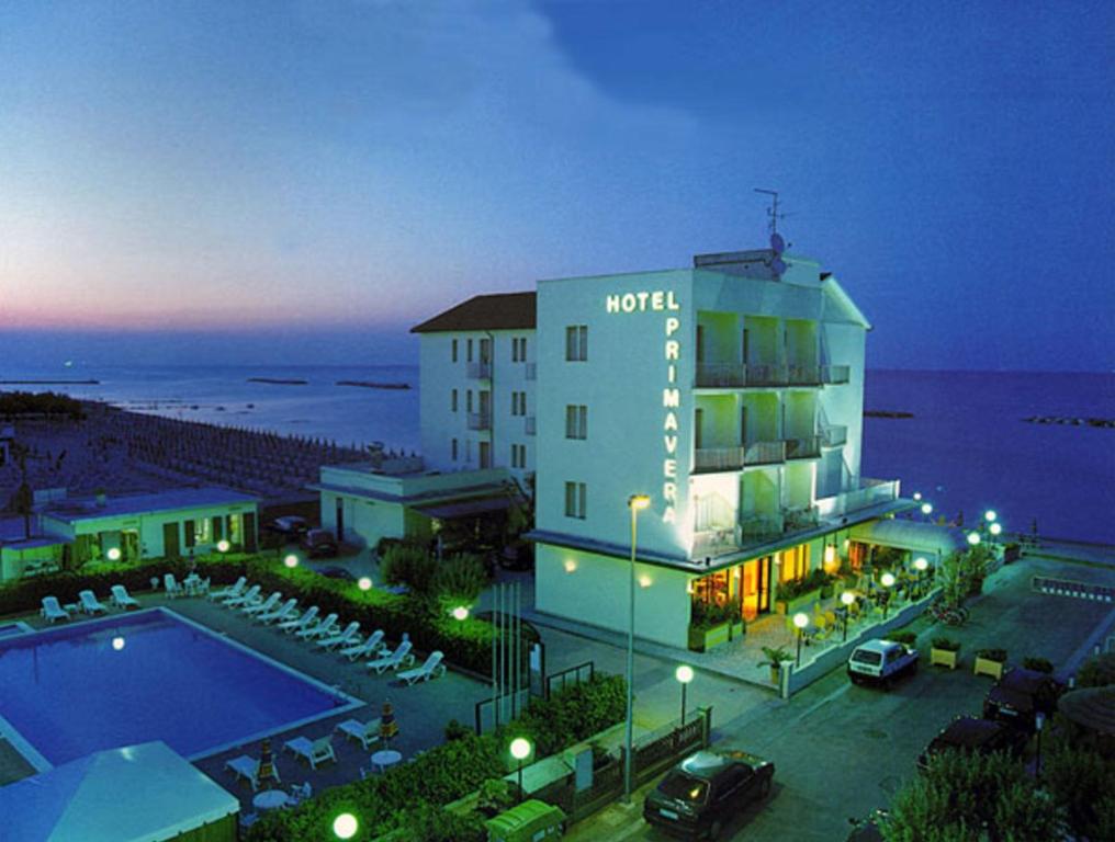 um hotel com piscina junto ao oceano à noite em Hotel Primavera sul mare em Lido di Savio