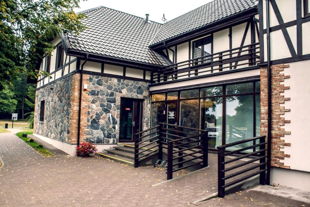 a house with a stone building with glass doors at Usmas muiža in Usma