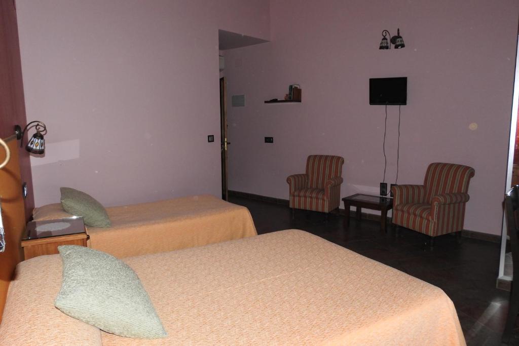 Habitación de hotel con 2 camas y 2 sillas en Casa Rural Monfragüe, en Villarreal de San Carlos