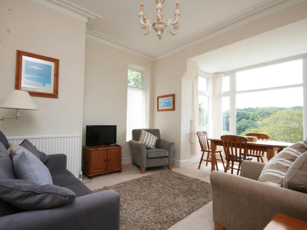 a living room with a couch and a tv and a table at 1 Hazeldene in Salcombe