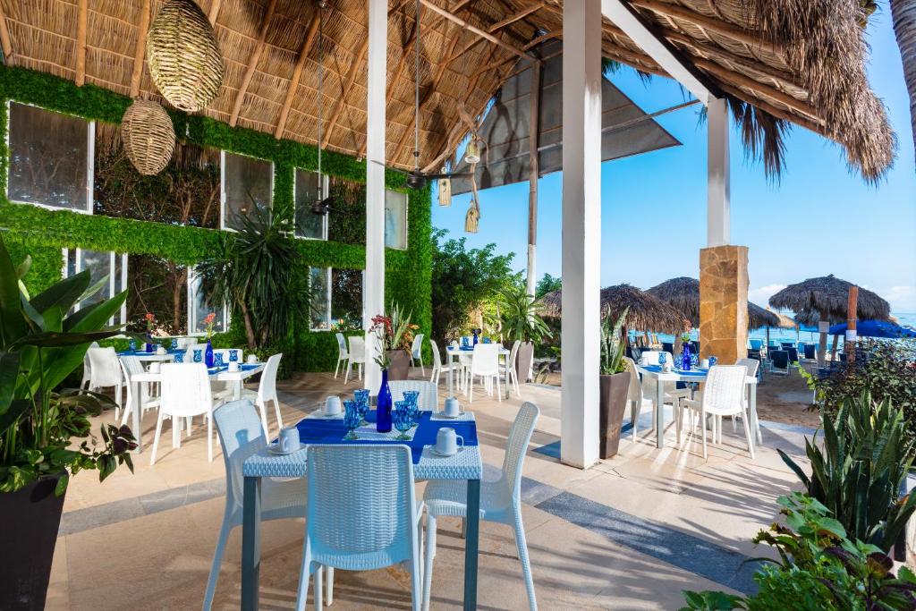a restaurant with tables and chairs and a view of the ocean at Blue Chairs Resort by the Sea - Adults Only in Puerto Vallarta