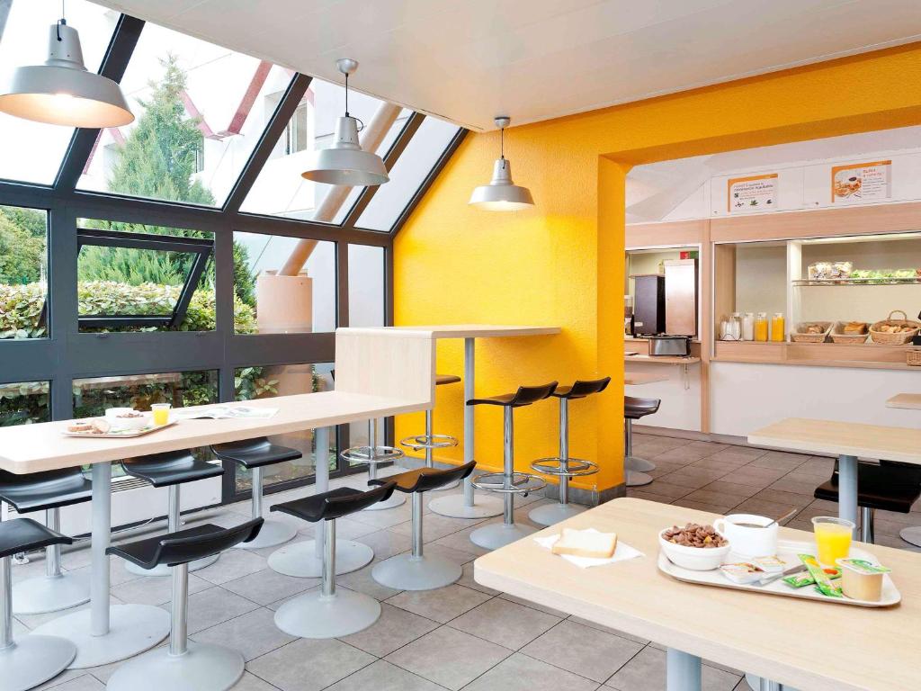 une cuisine avec des murs jaunes, des tables et des chaises dans l'établissement hotelF1 Pontarlier, à Pontarlier
