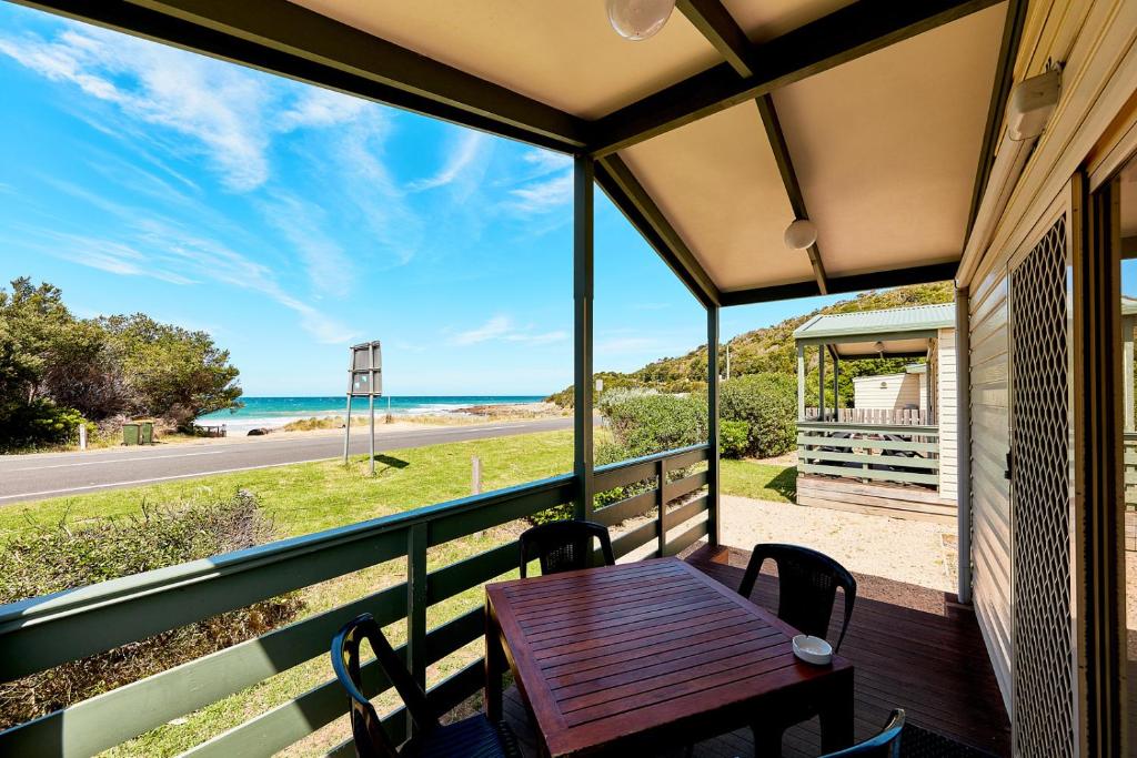 a table on a balcony with a view of the ocean at Kennett River Family Caravan Park in Wye River