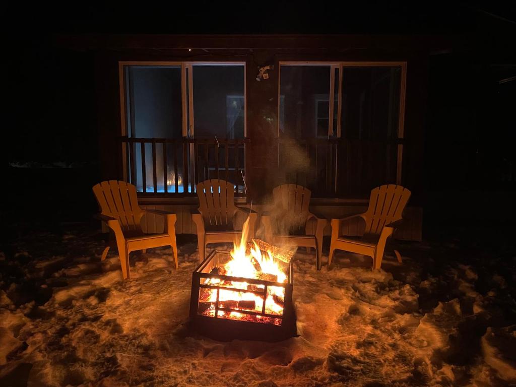 a fire pit with chairs and a table on a porch at 1 and Only Riverside Accommodations in Sable River