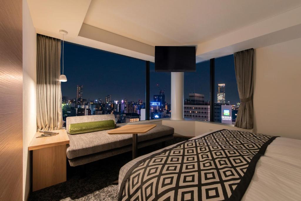 a bedroom with a bed and a view of a city at Hotel Vista Osaka Namba in Osaka