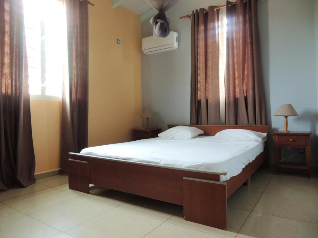 a bedroom with a bed and a window with curtains at Maison lumineuse à Bouillante avec vue sur la mer in Bouillante
