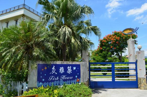 a blue gate with a palm tree in front of a building at Fish House 宜蘭獨棟別墅 戲水池 生態DIY 安農溪自行車 in Dongshan
