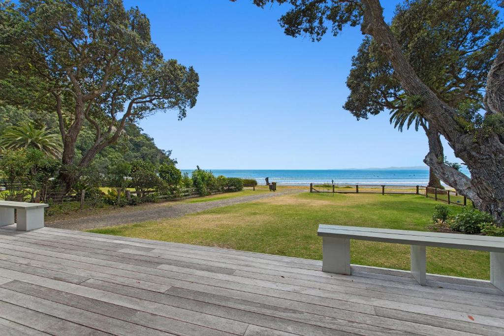 two benches sitting on a boardwalk near the beach at Kohi Point - Ohope Beachfront Holiday Home in Ohope Beach