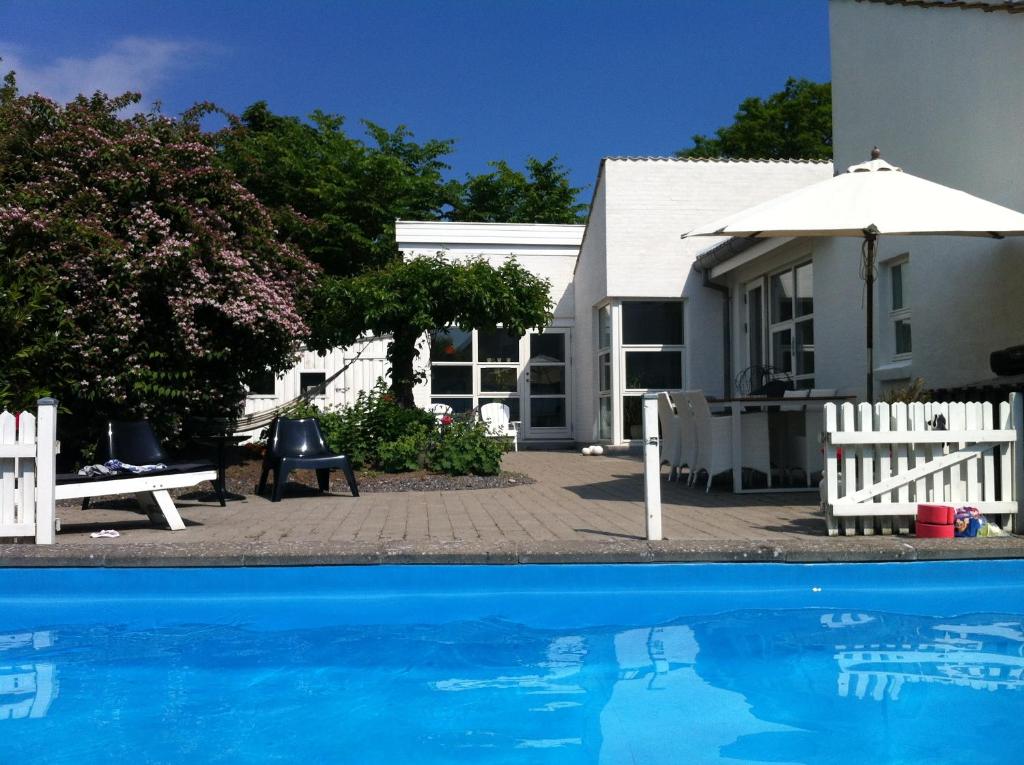 uma casa e uma piscina com um guarda-sol em Kathrines Bed & Breakfast em Svendborg