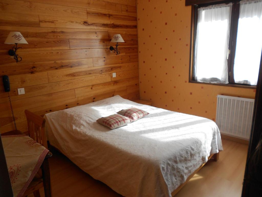 - une chambre avec un lit dans une pièce dotée de murs en bois dans l'établissement Hôtel L'Orée du Bois, à Xonrupt-Longemer