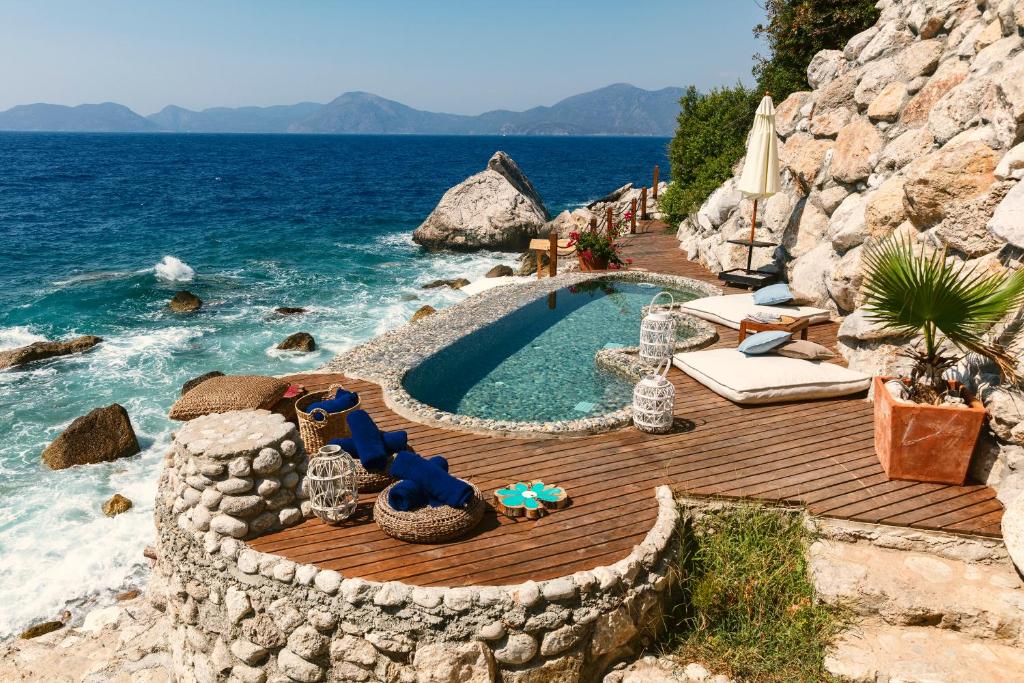 einen Pool auf einer Holzterrasse neben dem Wasser in der Unterkunft Nautical Hotel in Faralya