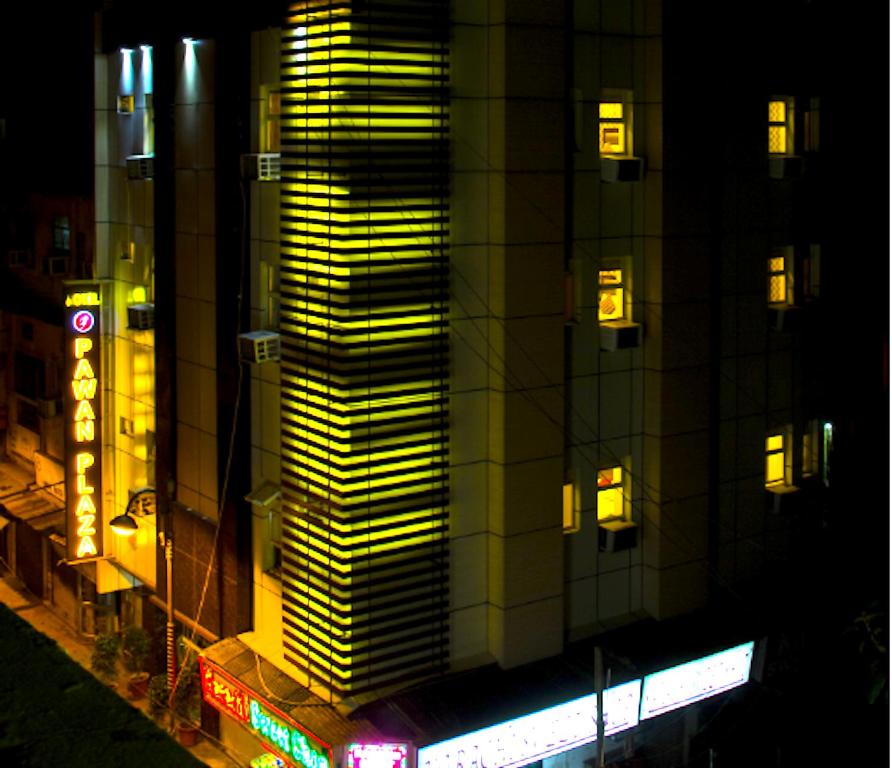 een hoog gebouw met gele lichten 's nachts bij Hotel Pawan Plaza Near Sir Ganga Ram Hospital in New Delhi