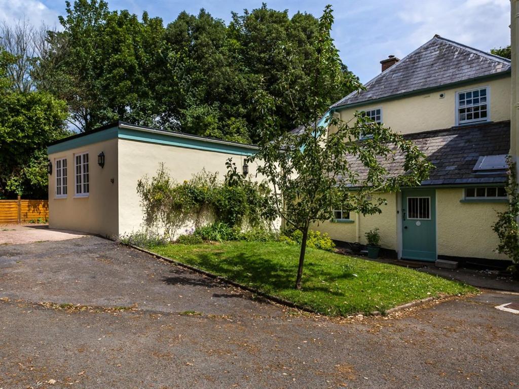 Una casa blanca con un árbol delante. en Vicarage Cottage, en Kenton