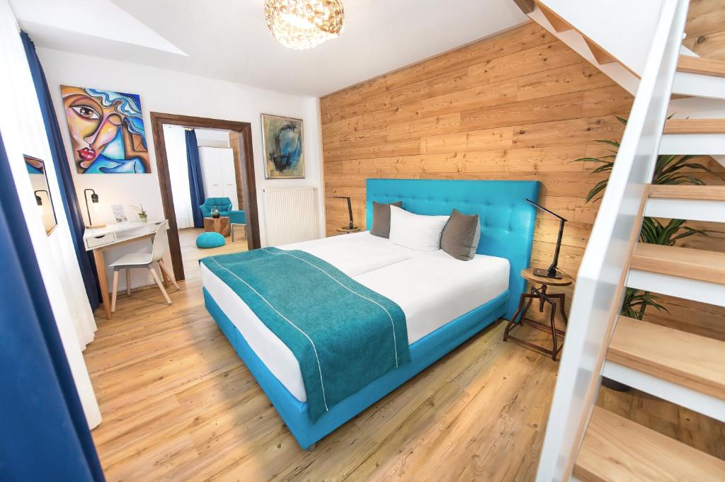 a bedroom with a blue bed and a staircase at Hotel Wohnbar in Bamberg