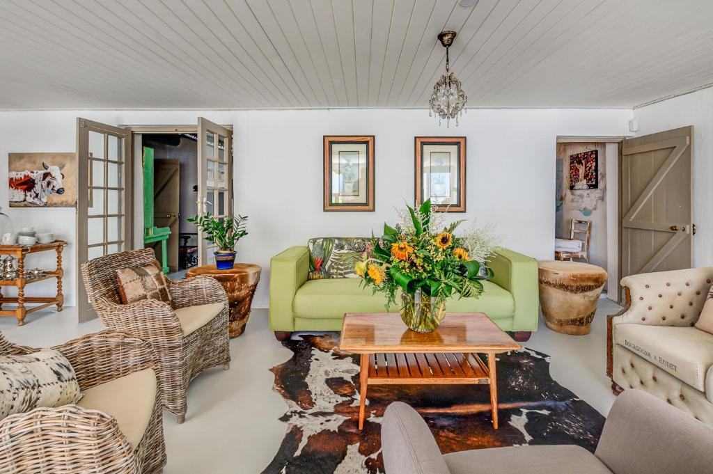 a living room with a green couch and chairs at De Kale Kat in Greyton