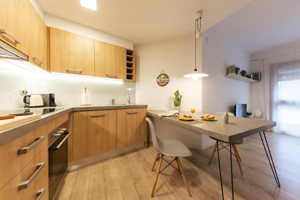 una cucina con armadi in legno e tavolo con sedie di Bravissimo La Mora a Girona