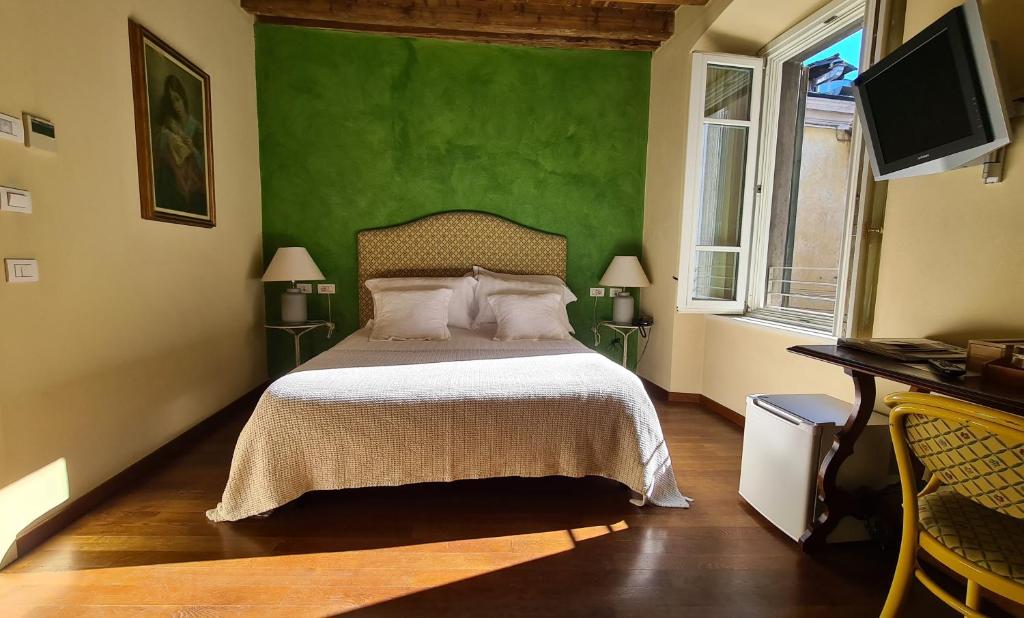 a bedroom with a bed with a green wall at Hotel Piazza Vecchia in Bergamo