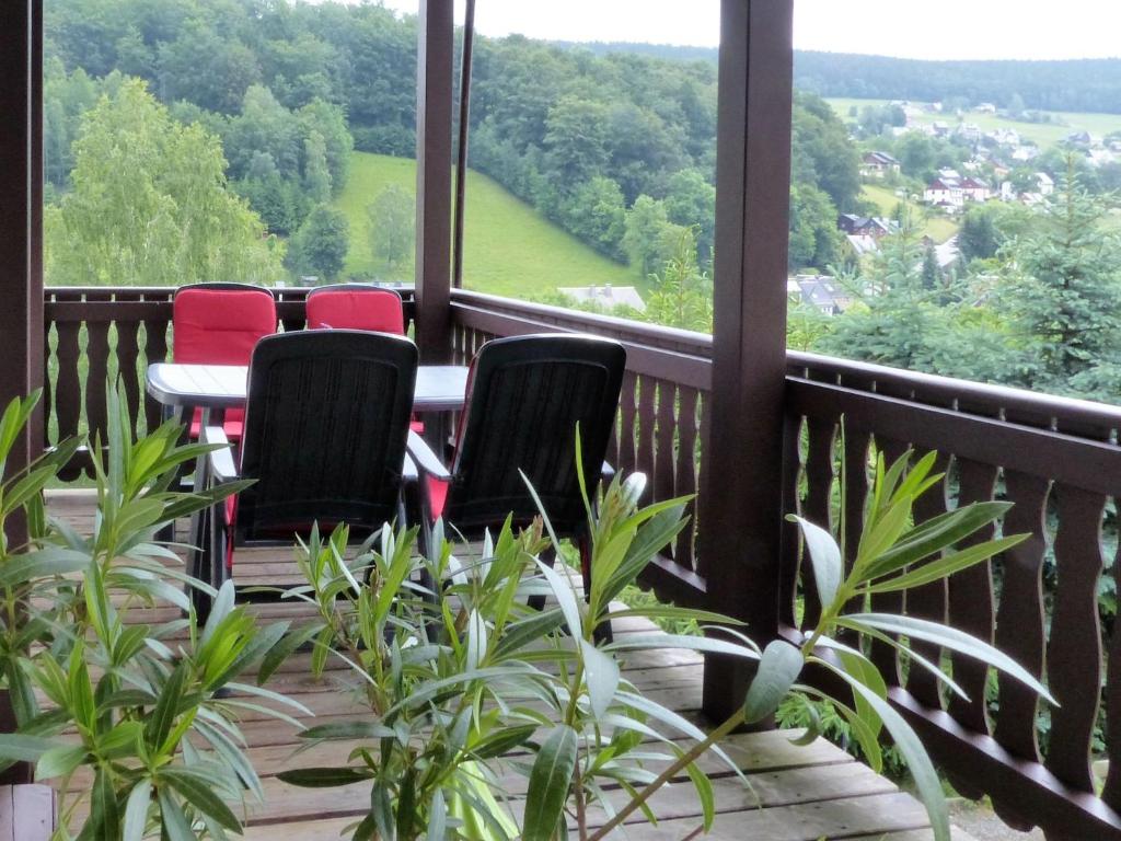a balcony with four chairs and a table and some plants at Cozy Apartment in Ore Mountains with Balcony and Garden in Breitenbrunn