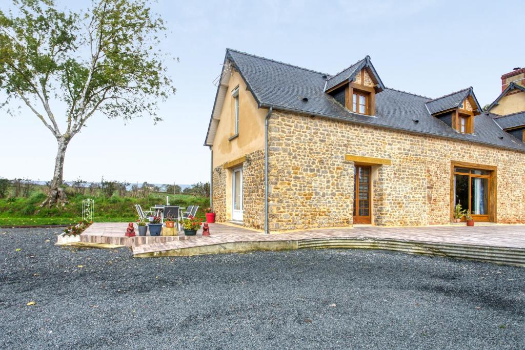 a stone house with a large driveway in front of it at Maison charmante à Saint-Marcouf avec jardin. in Saint-Marcouf